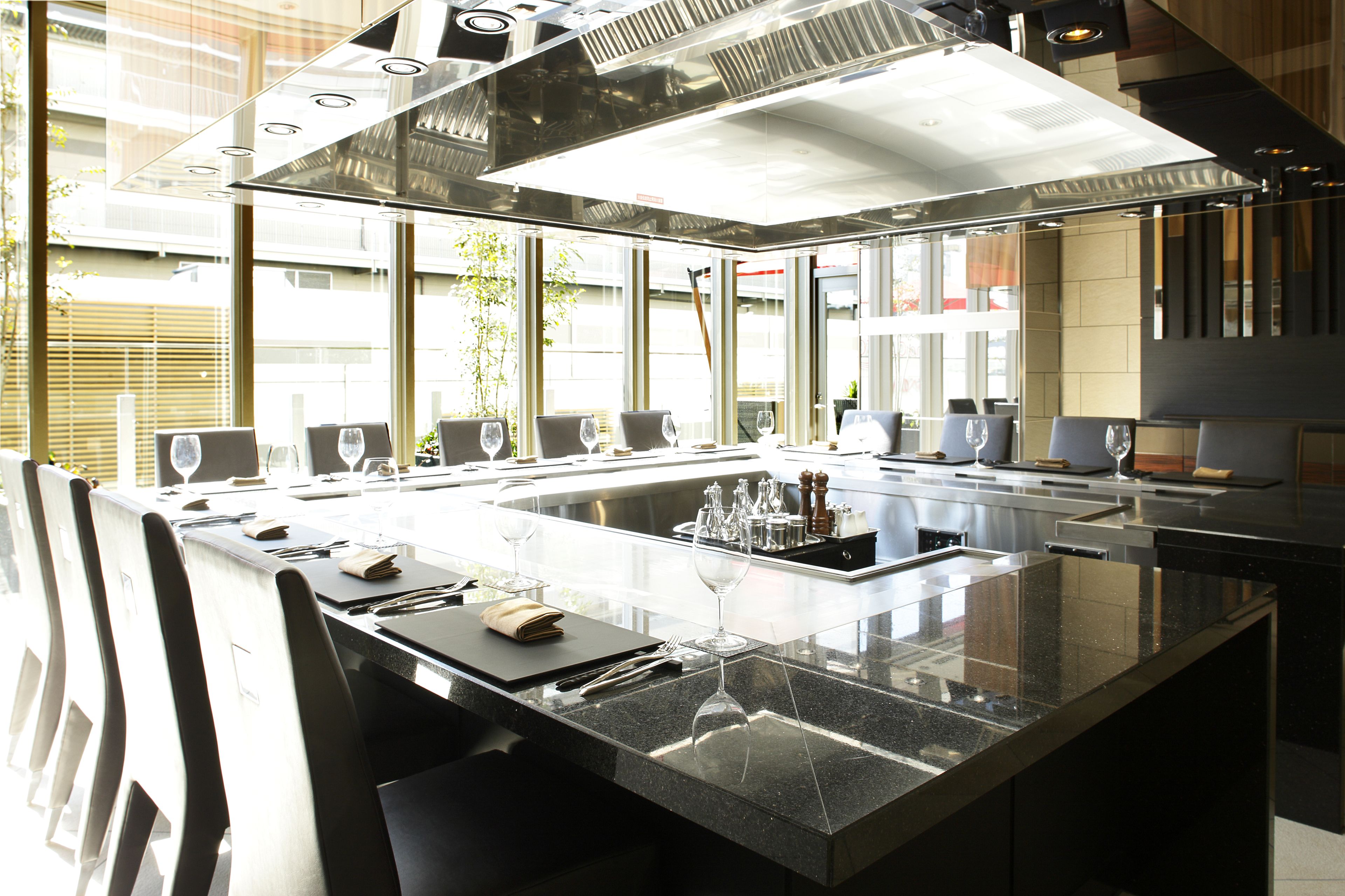 A modern kitchen with a central island, stainless steel appliances, and large windows offering a view of the city.