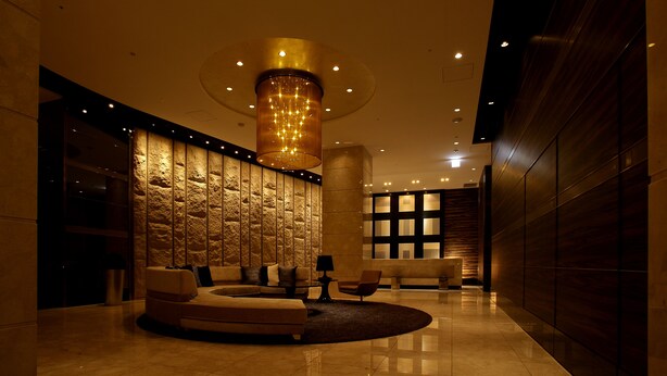 Een moderne lobby met een stenen muur, een rond zitgedeelte en een grote kroonluchter.