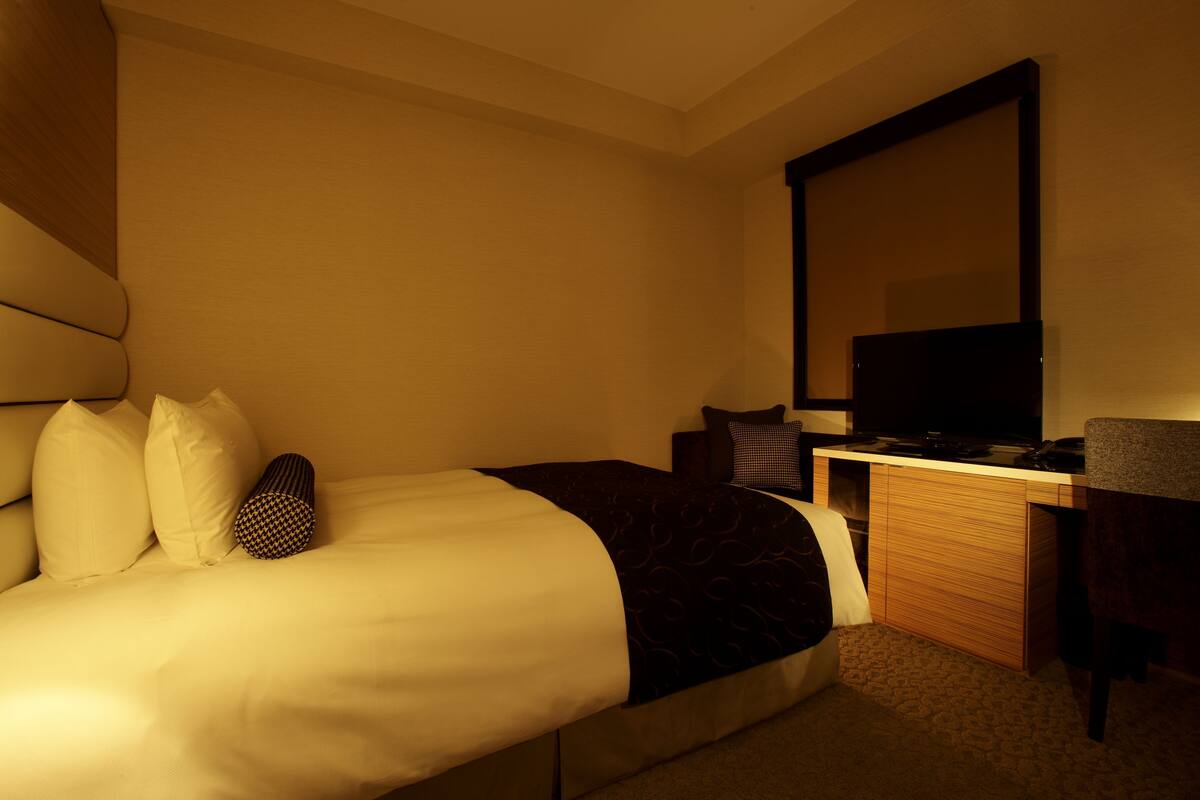 Une chambre d’hôtel équipée d’un lit, d’un bureau, d’une chaise et d’un téléviseur.