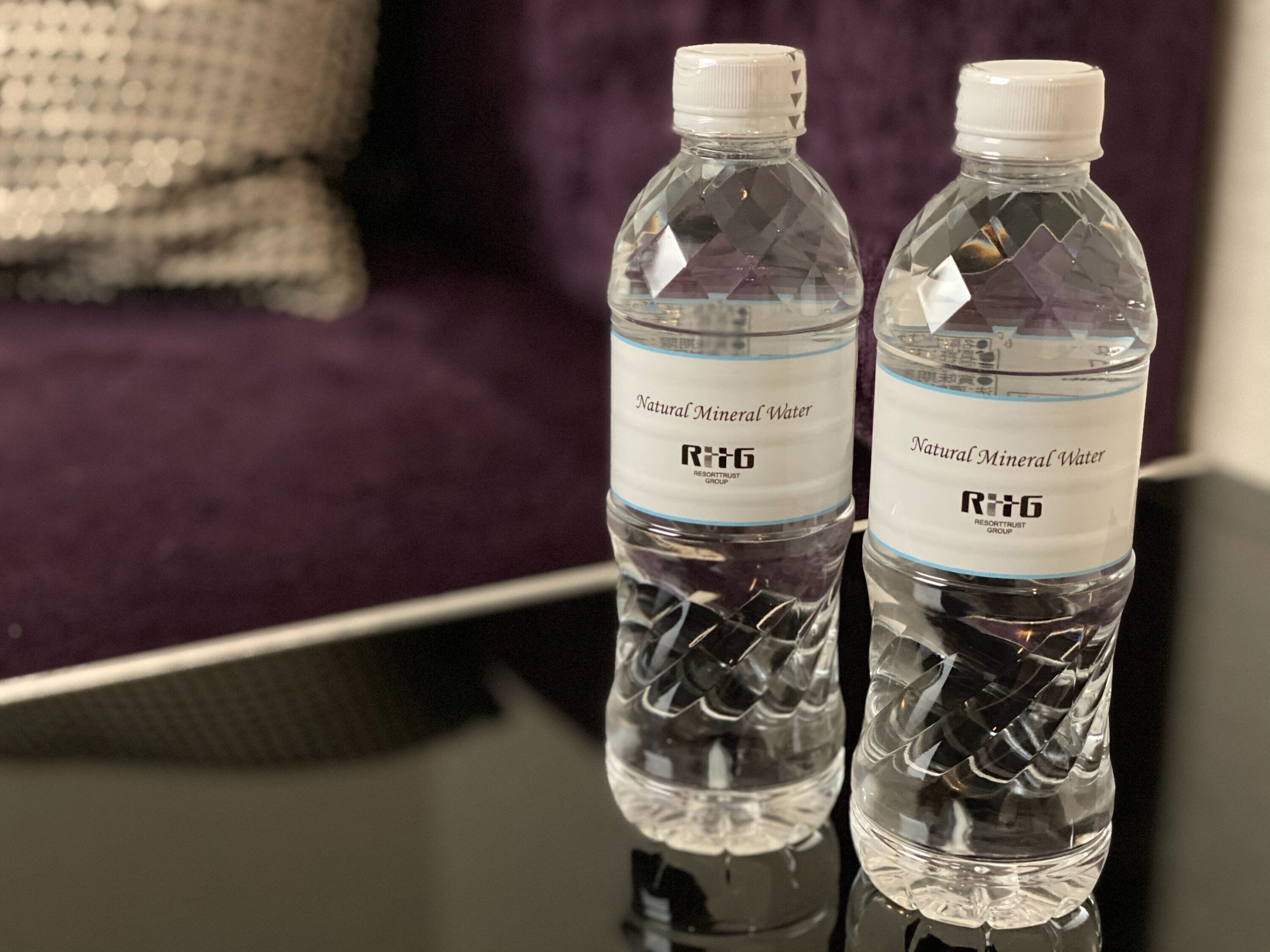 Twee flessen water met het label 'Natural Mineral Water' en het logo 'R+J RESORTTRUST GROUP'.