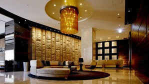 Een moderne lobby met een rond zitgedeelte, een grote decoratieve lamp en een structuurwand.