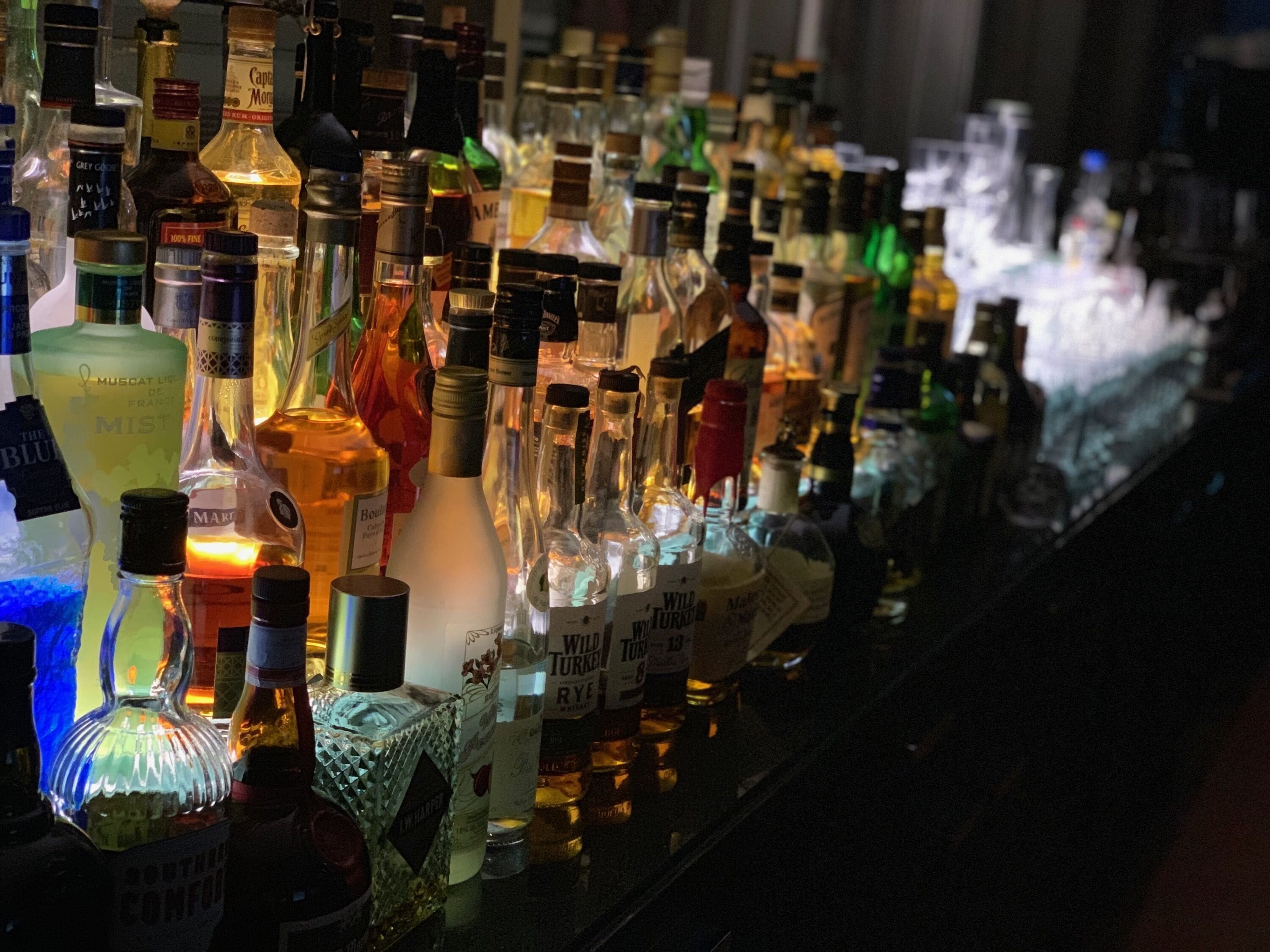 A bar with various bottles of alcohol, including whiskey and vodka, arranged on shelves.