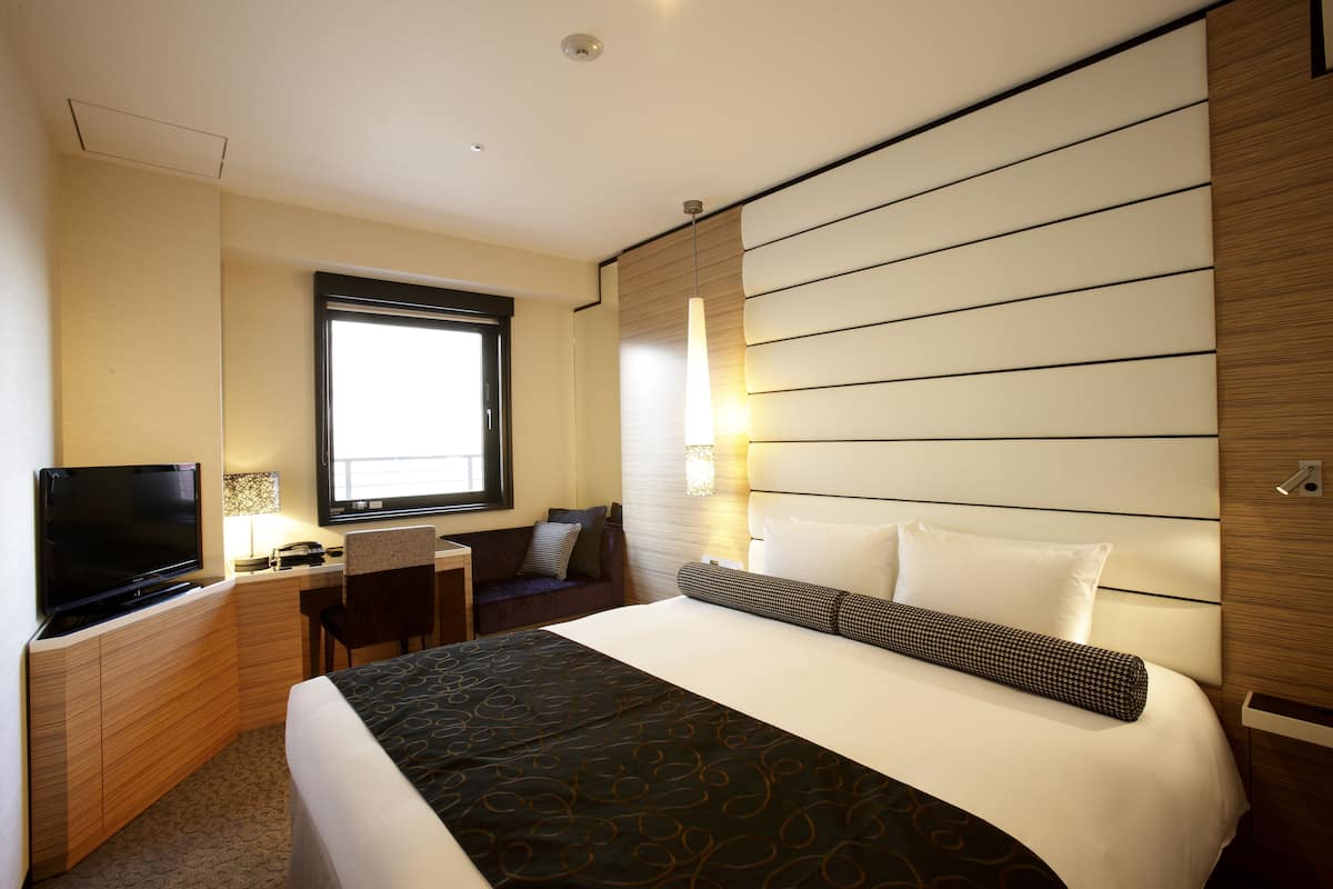 Une chambre d’hôtel avec un lit, une télévision, un bureau et une fenêtre.