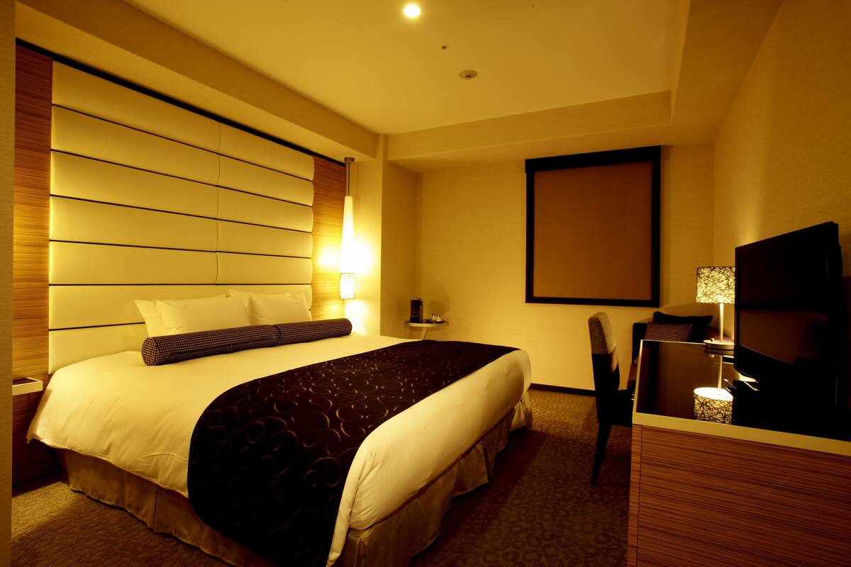 Une chambre d’hôtel avec un grand lit, des tables de chevet, un téléviseur à écran plat et un téléviseur fixé au mur.