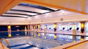 An indoor swimming pool with a tiled floor, a pool ladder, and lounge chairs around the perimeter. - Grand Metropark Hotel Shenyang (Shenyang)