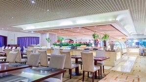 A modern hotel lobby with dining areas, a central food station, and a reception desk. - Grand Metropark Hotel Shenyang (Shenyang)