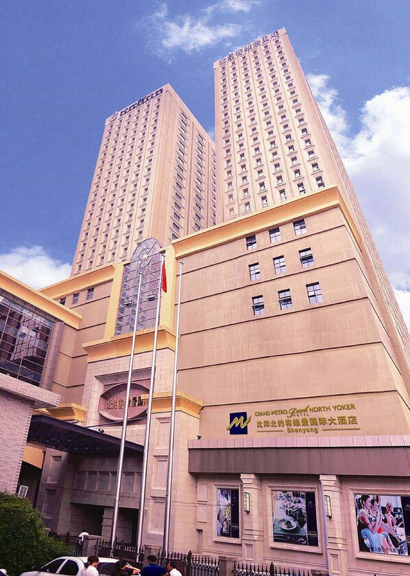 A tall hotel building with multiple floors and a prominent entrance. - Grand Metropark Hotel Shenyang (Shenyang)