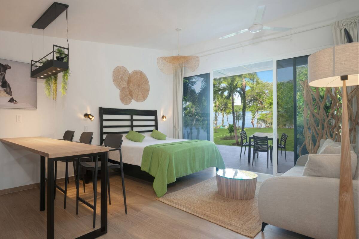 Moderni hotellihuone, jossa on sänky, ruokailutila ja sohva.