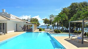 A pool area with a view of the sea, outdoor seating, and a covered patio. - Bocas del Mar Hotel (Boca Chica)