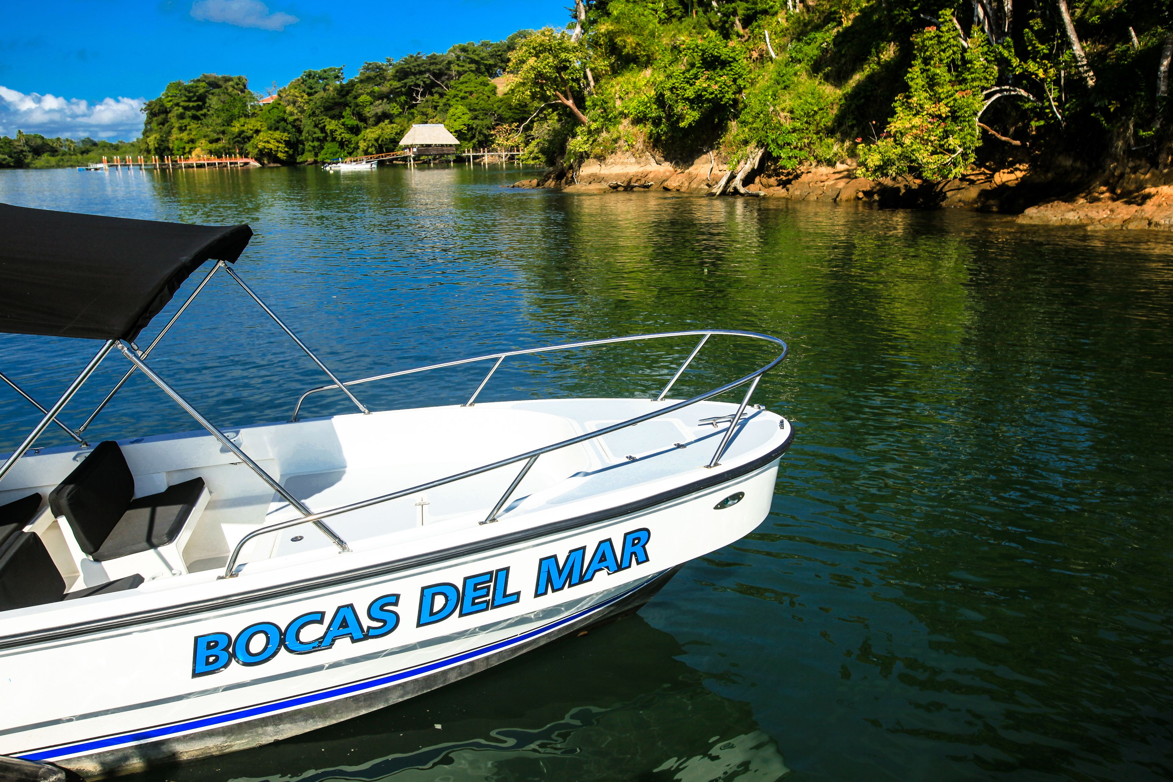 A boat named "Bocas Del Mar" with a covered seating area and metal railings.