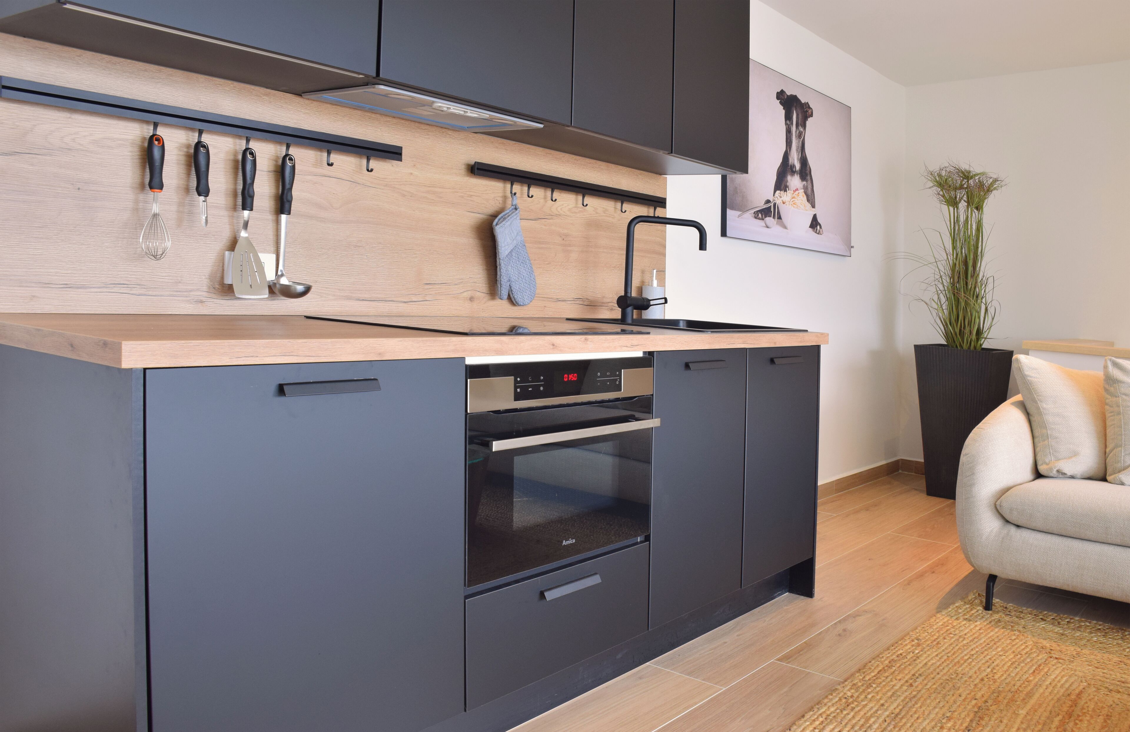 A modern kitchen with a wooden countertop, black cabinets, and a built-in oven.
