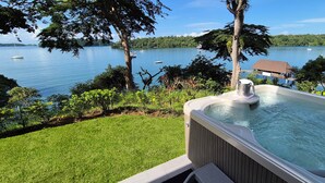A hot tub on a deck overlooking a lake with boats and a house in the background. - Bocas del Mar Hotel (Boca Chica)