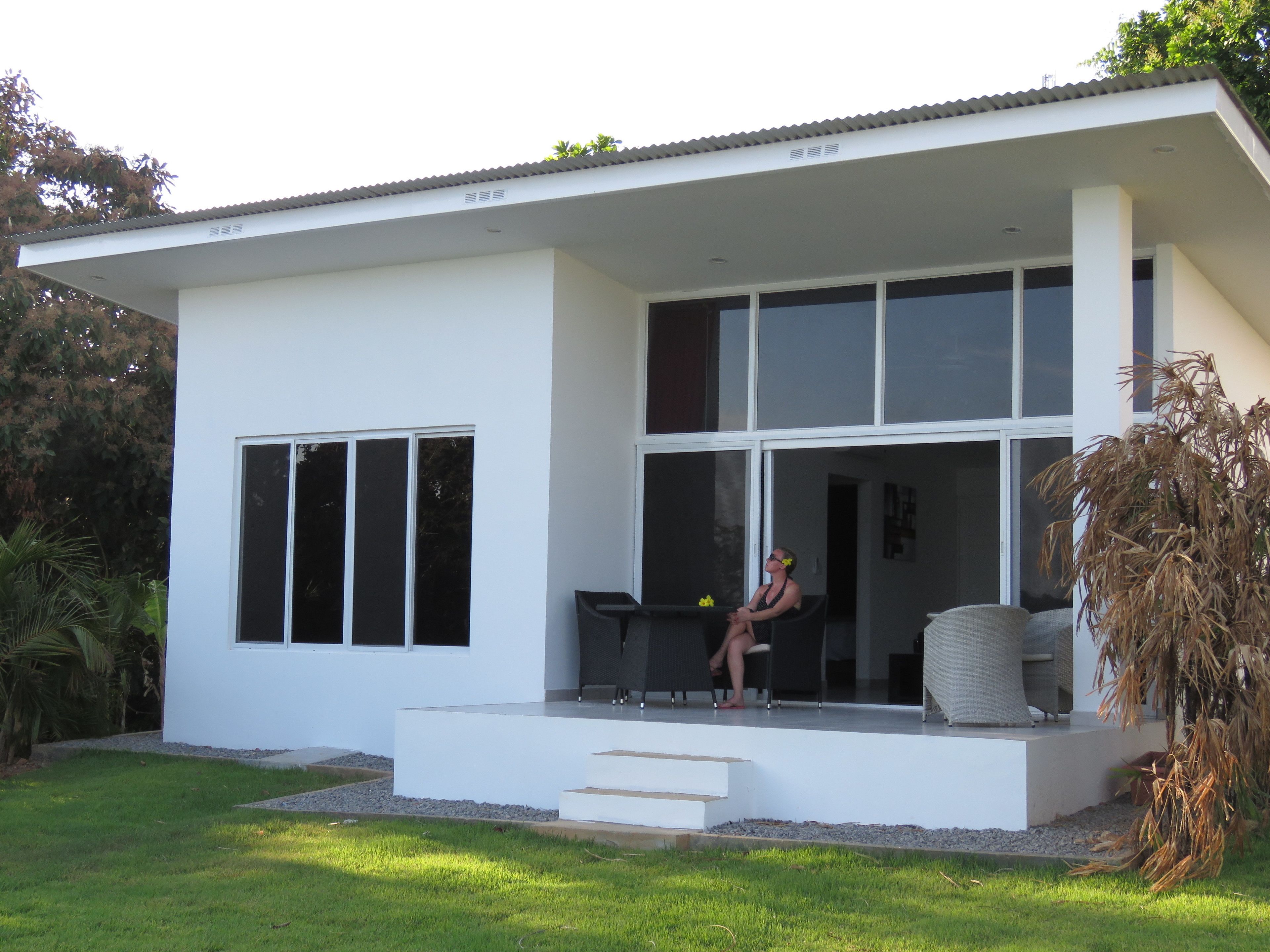 Ein modernes Haus mit flachem Dach, großen Fenstern und einer überdachten Veranda.