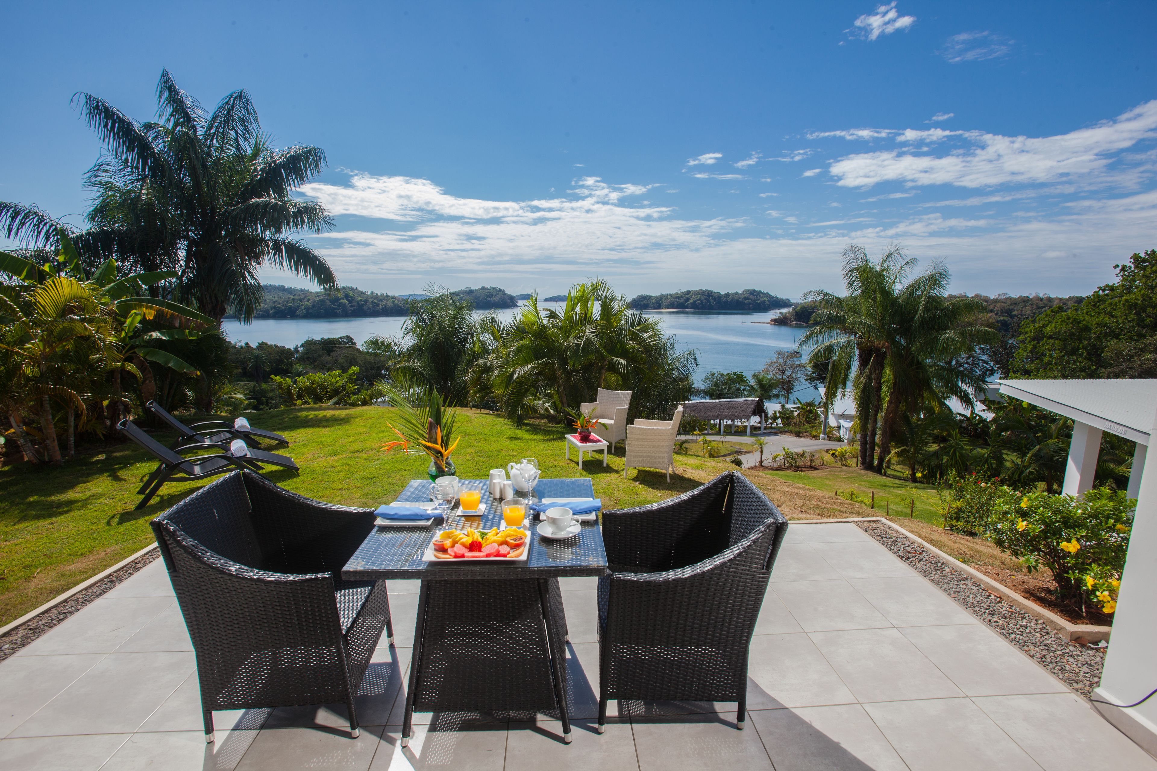 A patio with a table set for breakfast, overlooking a scenic view of a lake and hills.