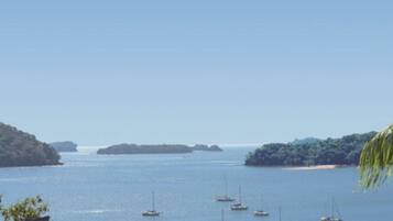 A coastal view with several boats on calm waters, surrounded by lush greenery and distant islands.