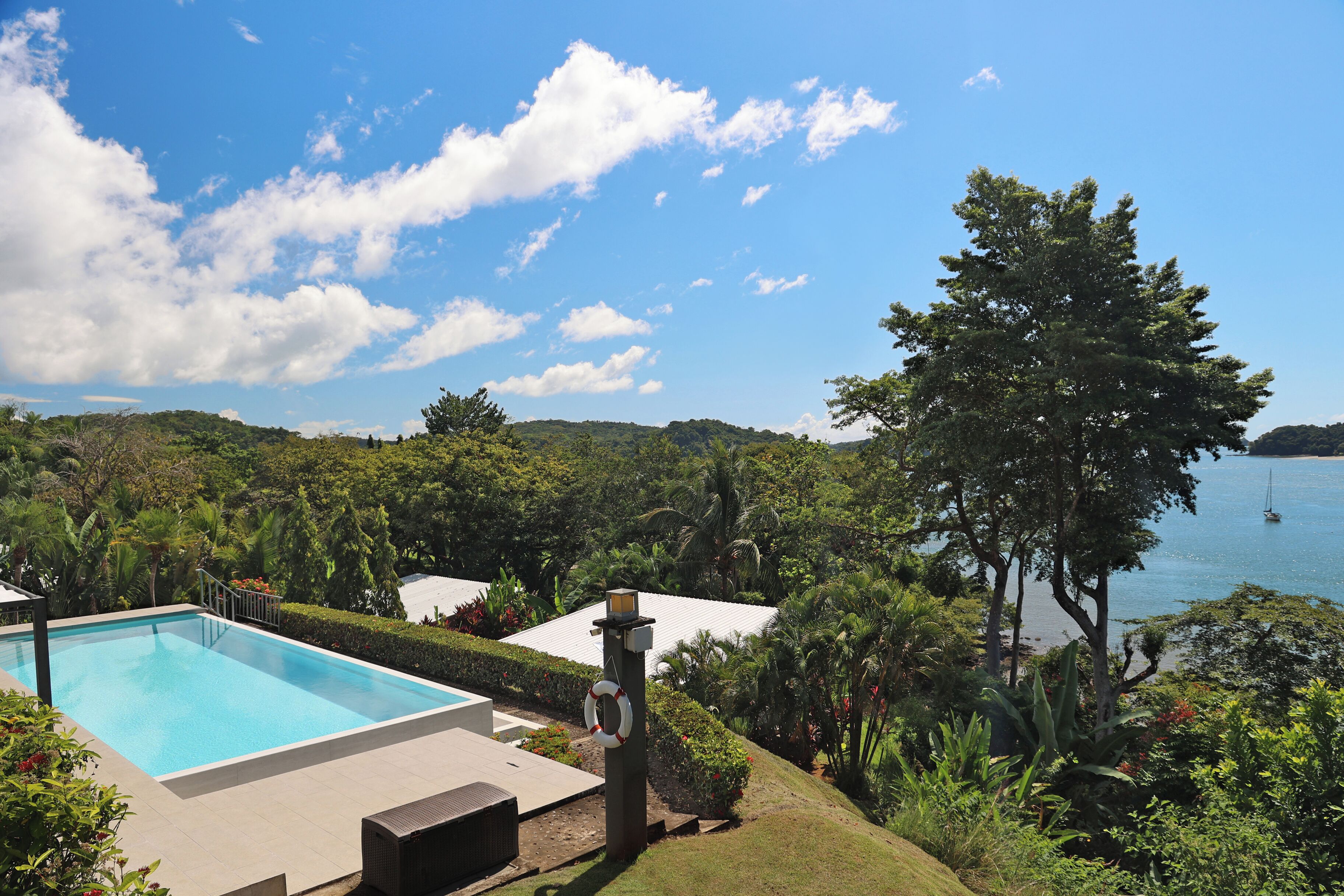 A swimming pool with a view of a body of water and hills in the background.