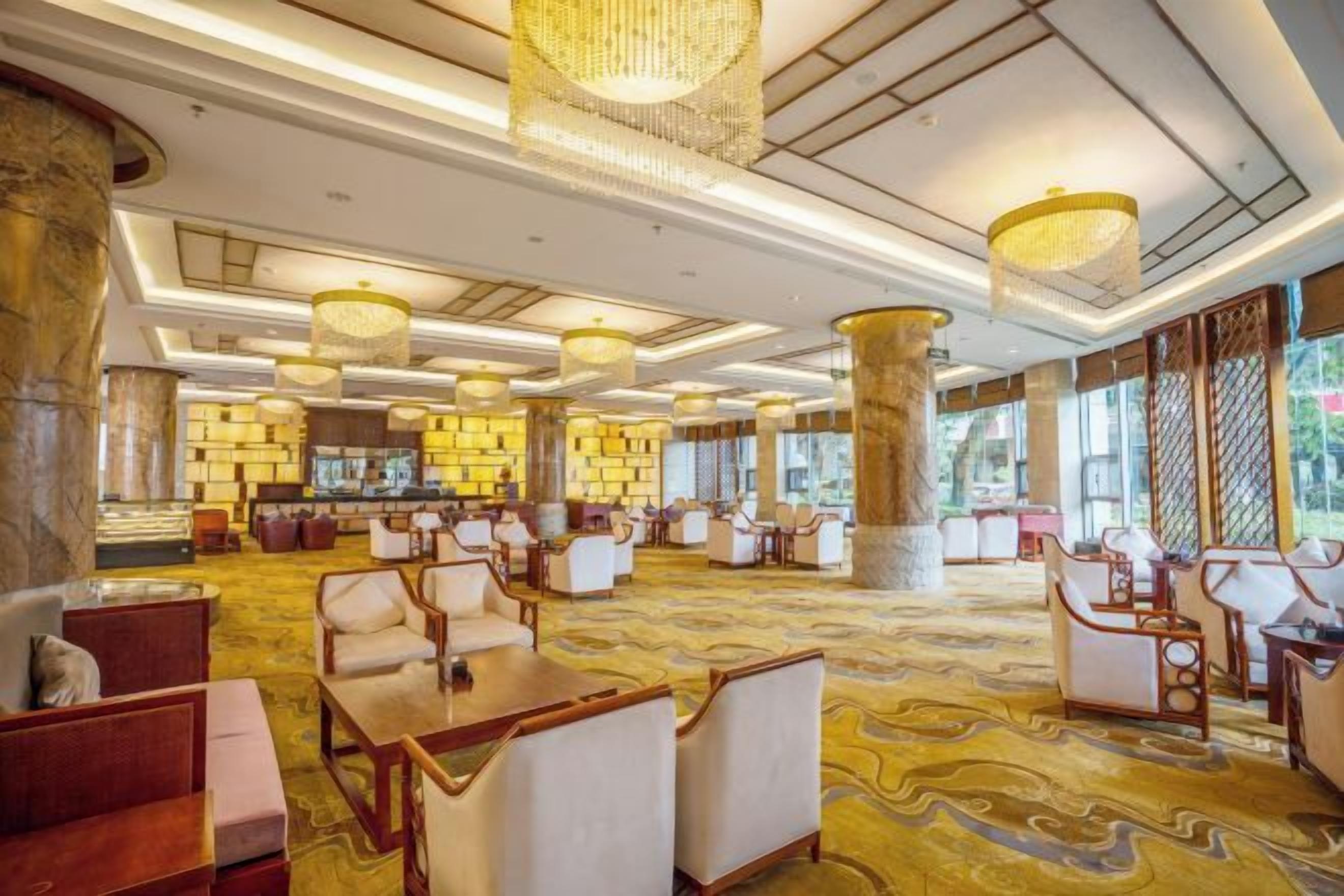 A spacious lobby with multiple seating areas, large columns, and a patterned carpet.