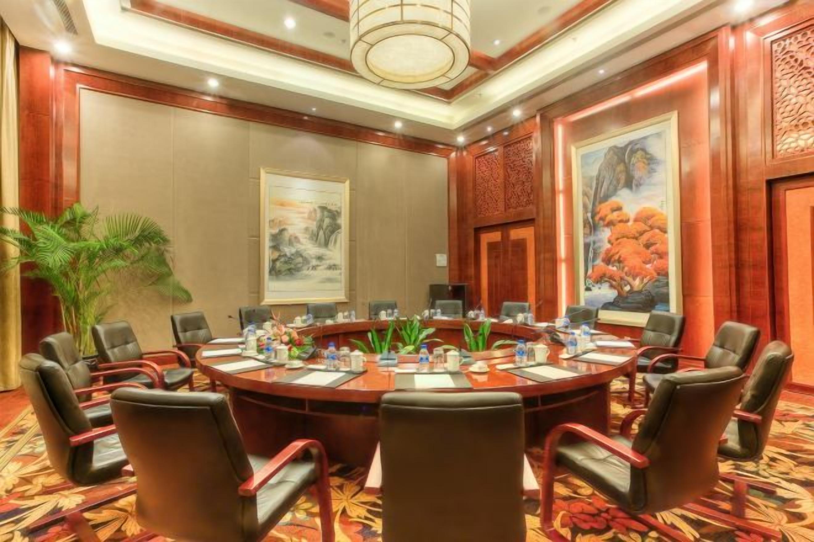 A conference room with a round table, chairs, and a large painting on the wall.