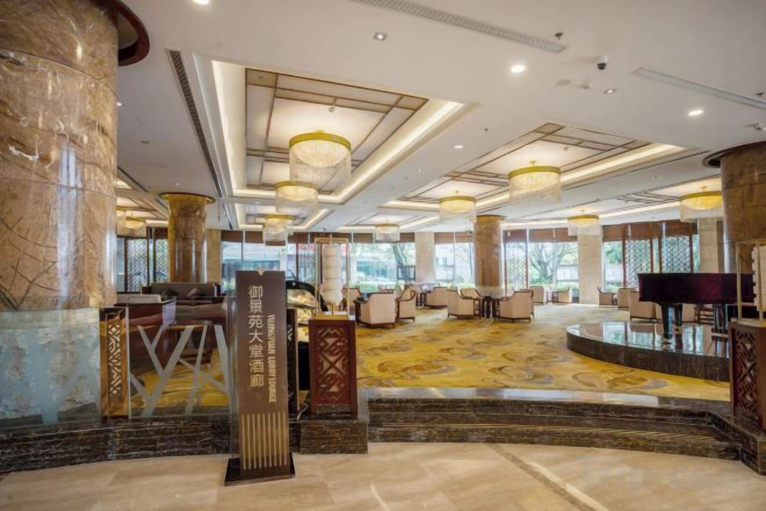A spacious lobby with a marble floor, a reception desk, and a piano.