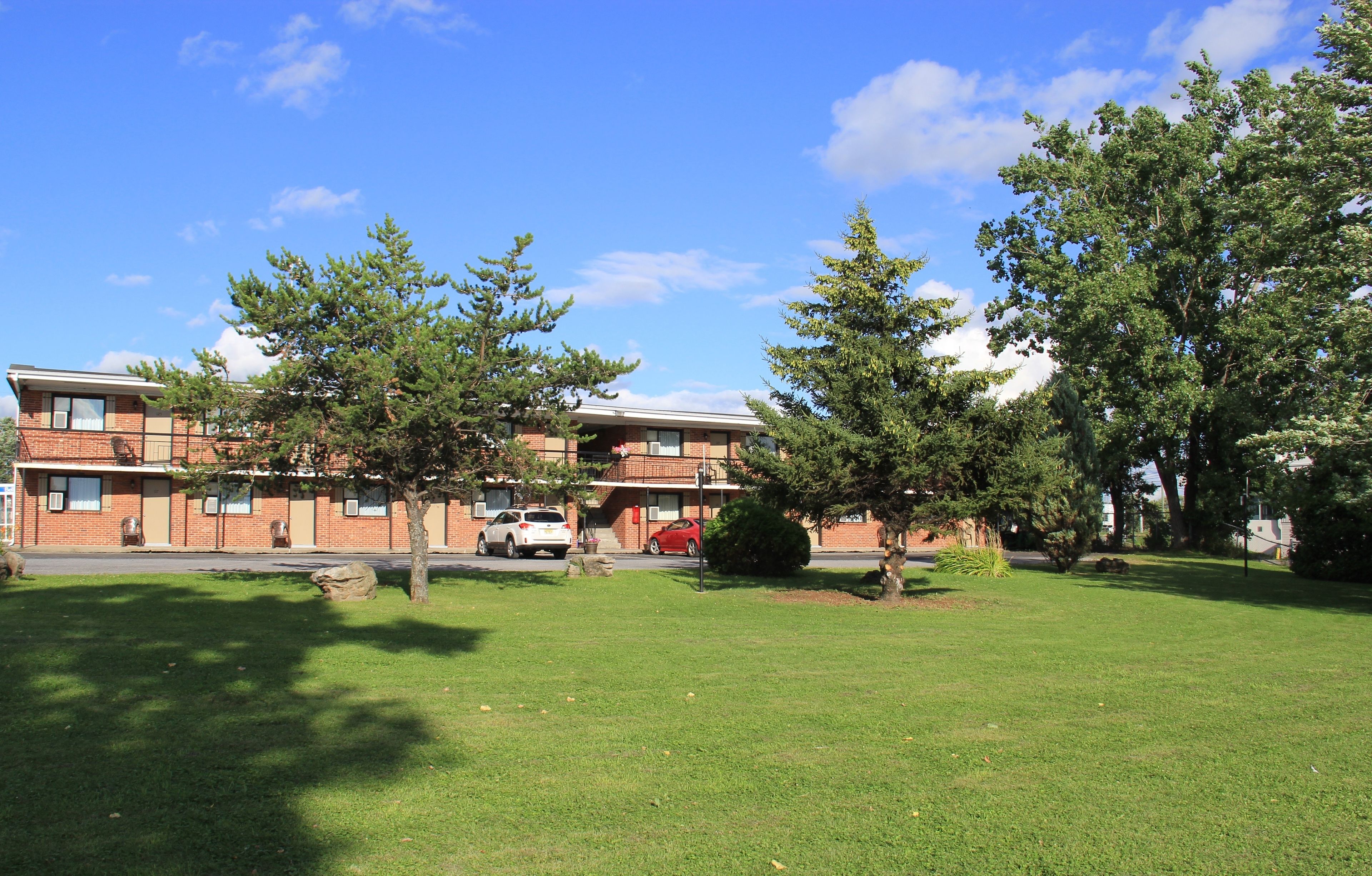 A brick building with multiple windows and a lawn in front.