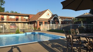 Um motel com piscina, área de estar externa e espaço cercado.