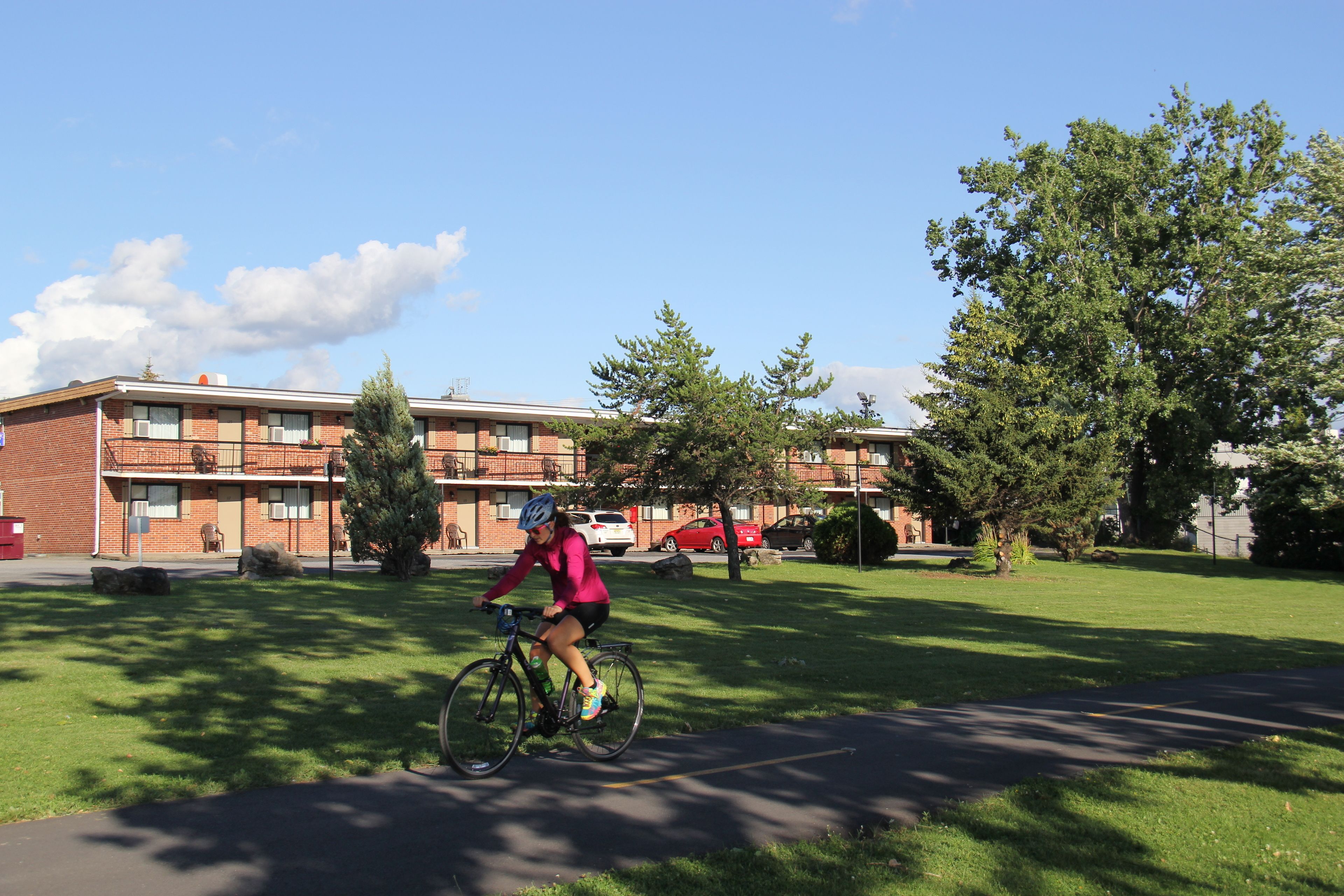 Un ciclista en un sendero, con un edificio al fondo.