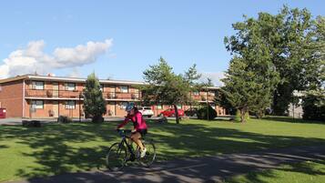 Un ciclista en un sendero, con un edificio al fondo.