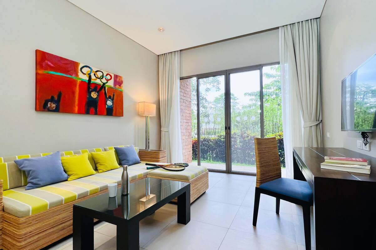A modern living room with a sofa, coffee table, and a TV mounted on the wall.