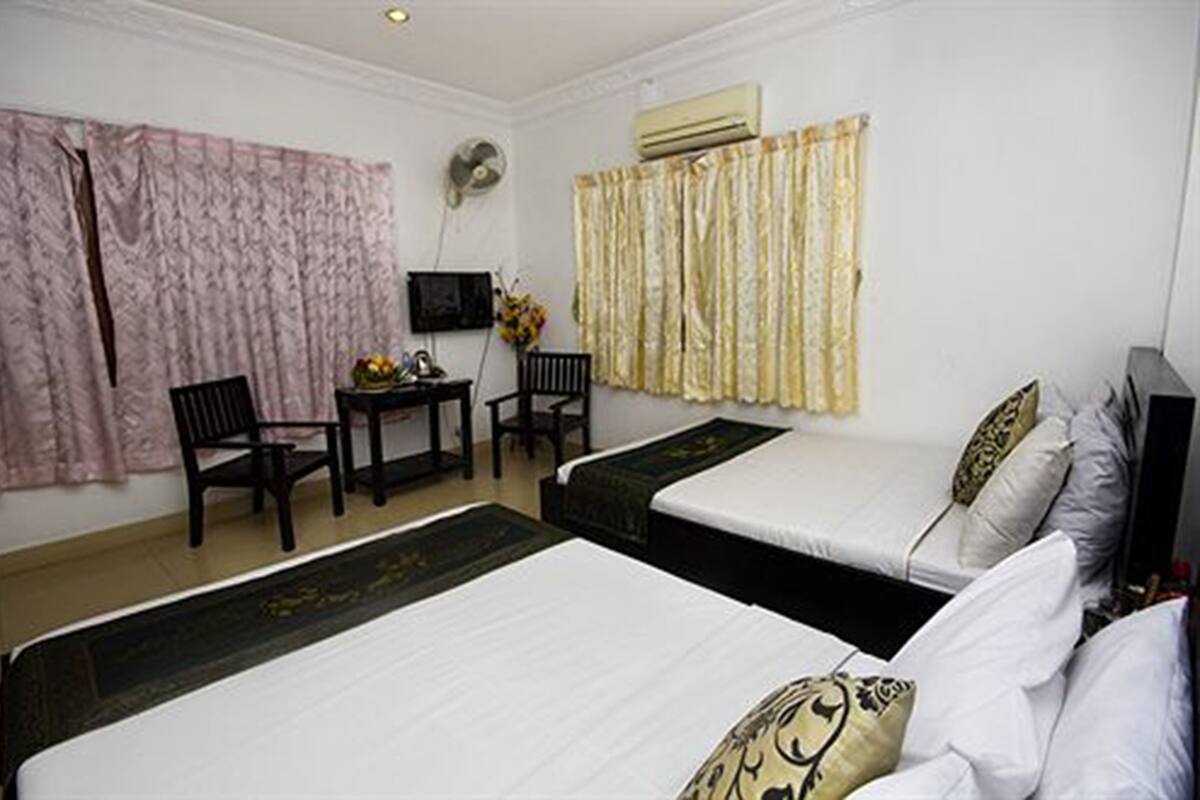 Una habitación de hotel con dos camas, un escritorio con sillas, un televisor y cortinas.
