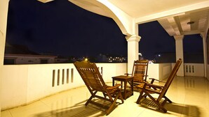 An outdoor patio with two wooden chairs and a small table, overlooking a cityscape at night. - King Boutique Hotel (Siem Reap)