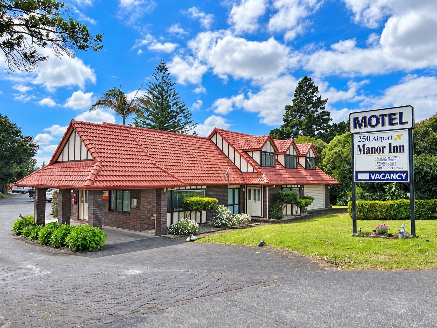 Un motel con techo de tejas rojas, un letrero que indica habitaciones agotadas y un anuncio para el 250 Airport Manor Inn.