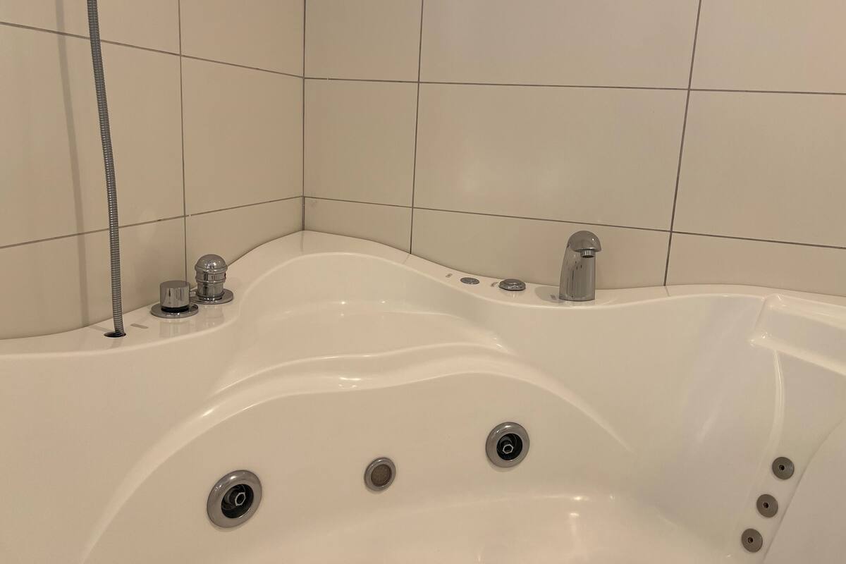 A white bathtub with a showerhead, a faucet, and three drain holes.