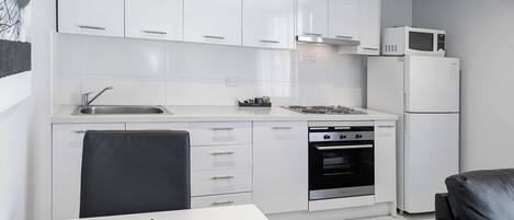 A modern kitchen with white cabinets, a built-in microwave, a refrigerator, and a stove.