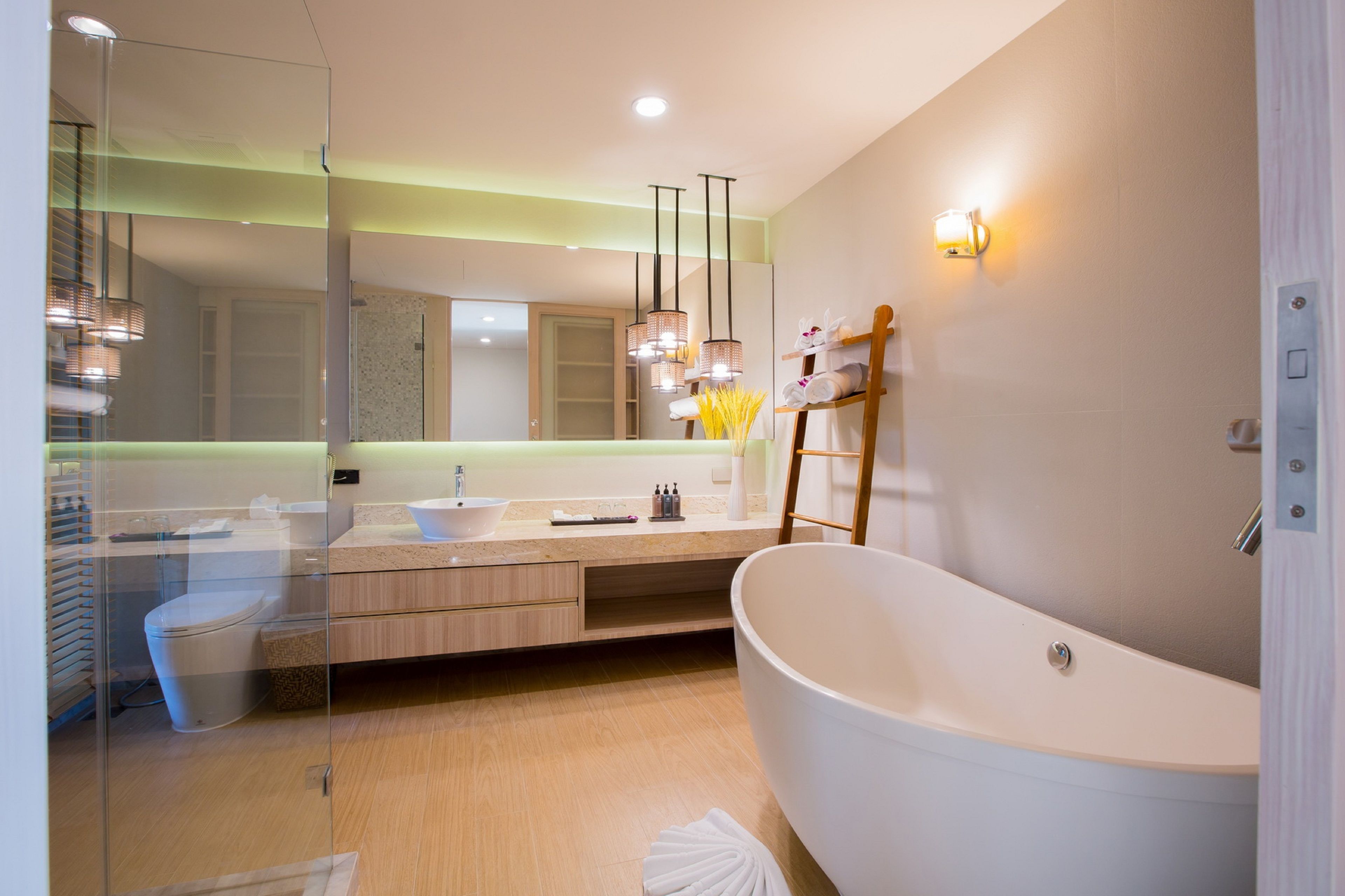 Un baño moderno con una bañera independiente, una ducha con mampara de vidrio y un lavamanos con espejo.