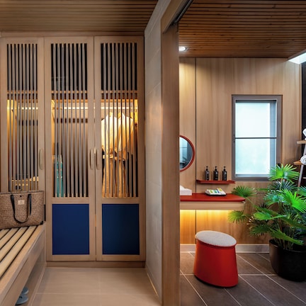 A modern bathroom with a wooden vanity, a sink, a mirror, and a potted plant.