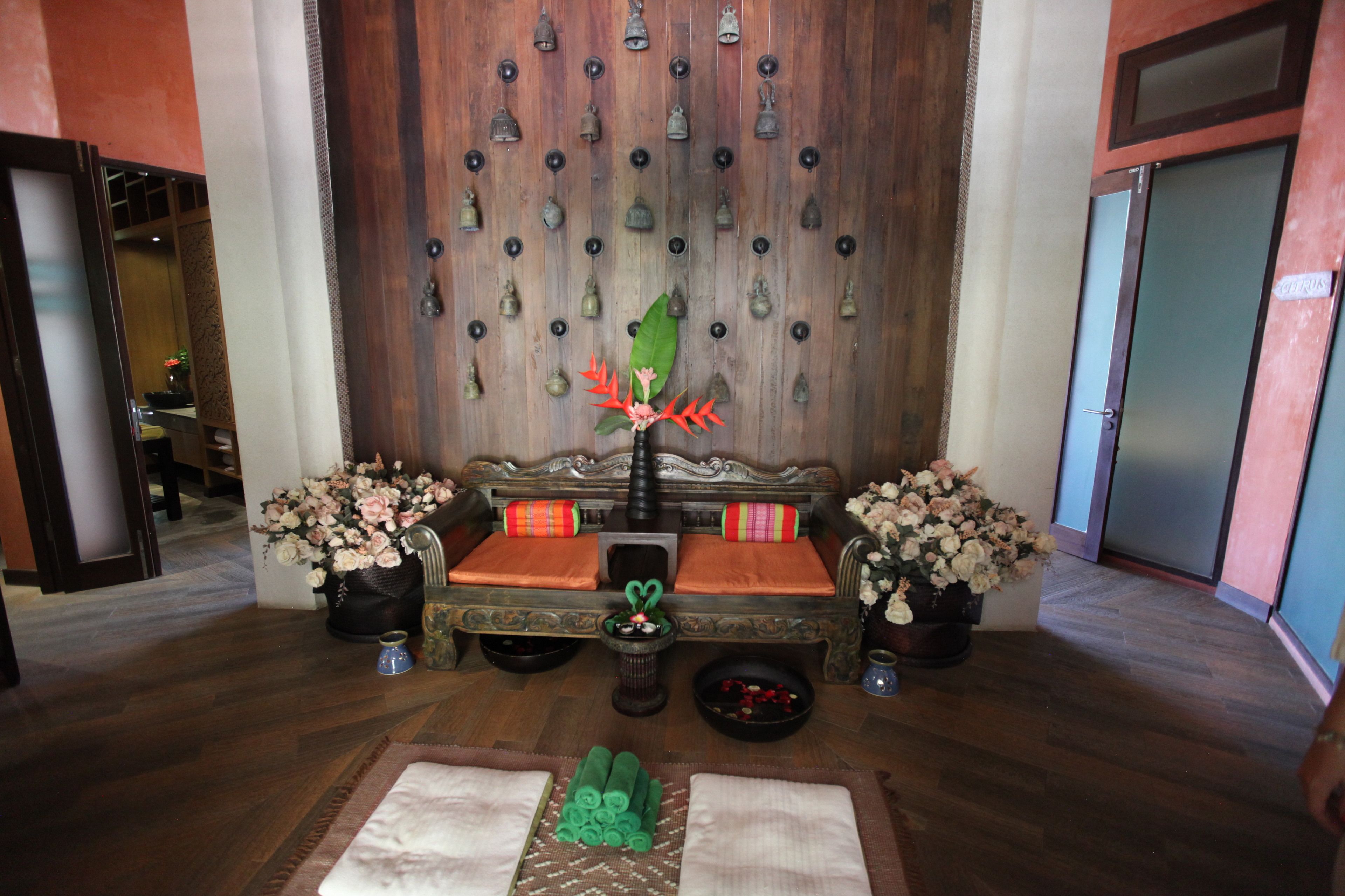 A traditional room with a wooden wall, a sofa with cushions, a small table with a vase, and a decorative bell wall.