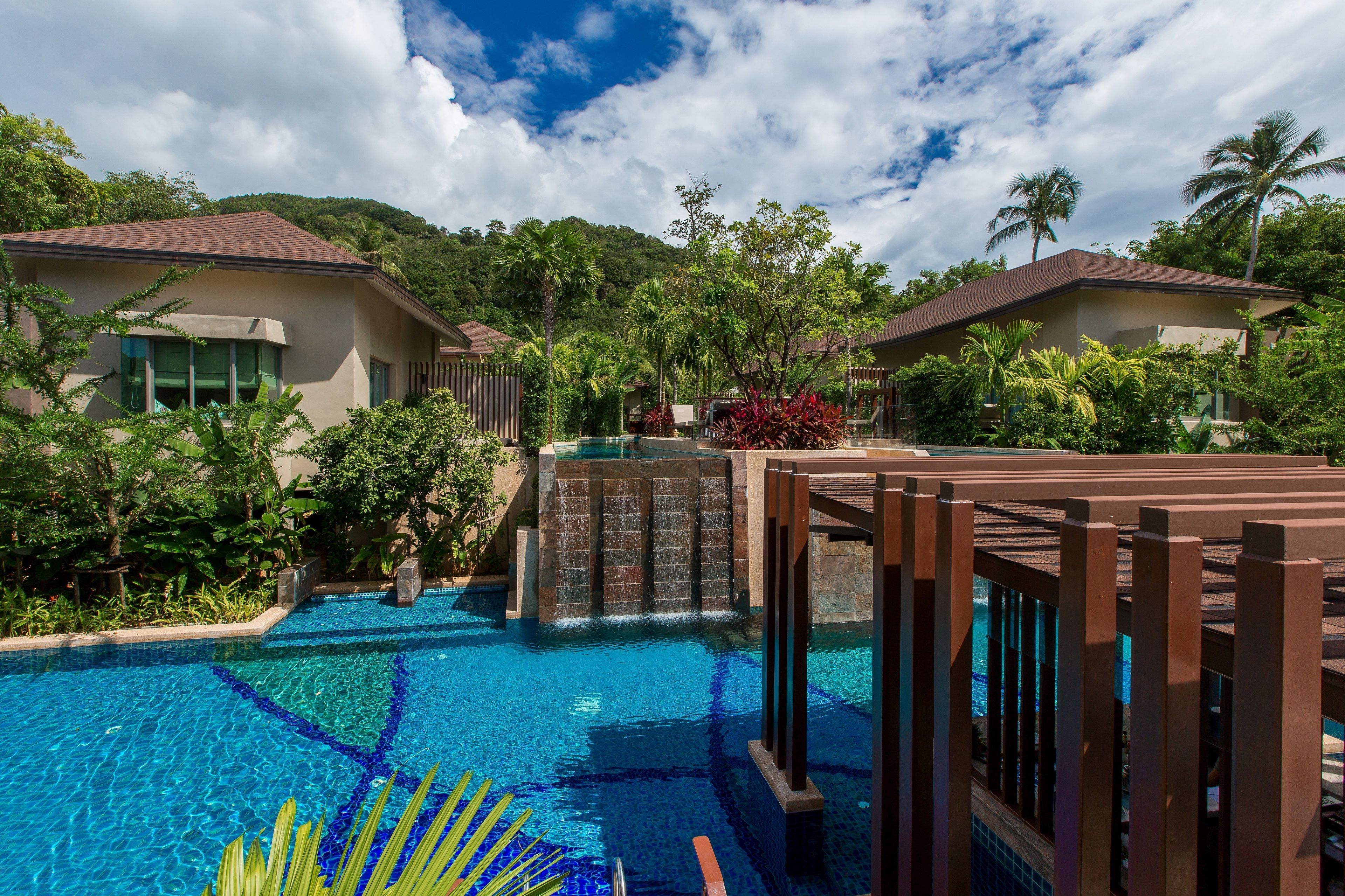 Un resort con piscina, palmeras y una cascada.