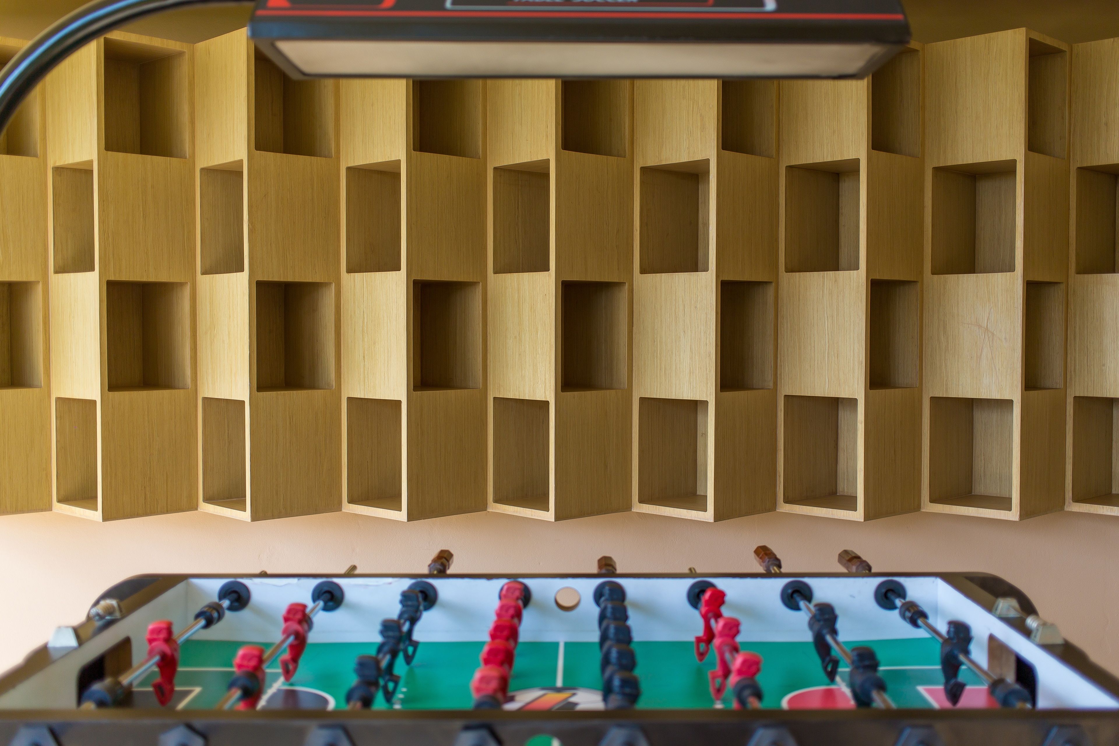 A room with a foosball table and wooden shelving units.