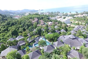Un resort con diversi edifici in stile bungalow, una piscina centrale e vista sull'oceano.