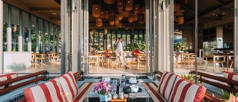 Un restaurant moderne doté d’un espace de restauration central, de grandes fenêtres et de lanternes suspendues.