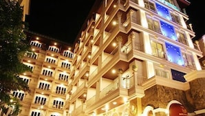 A multi-story hotel with balconies and a stone facade.
