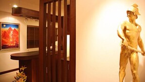 A room with a wooden door, a statue, and a painting on the wall.