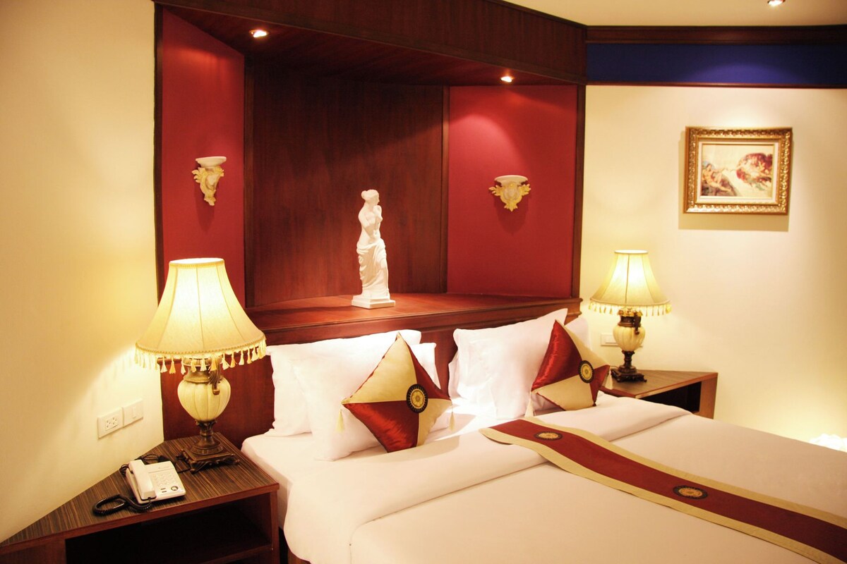 A hotel room with a bed, two bedside tables, a telephone, and a decorative statue on the headboard.