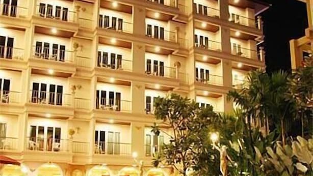 A multi-story hotel with balconies and a swimming pool.