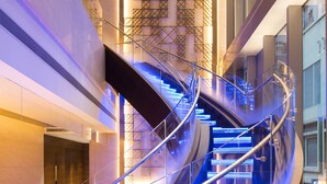 A modern spiral staircase with glass railings and illuminated steps. - Hotel Indigo Hong Kong Island by IHG (Hong Kong)
