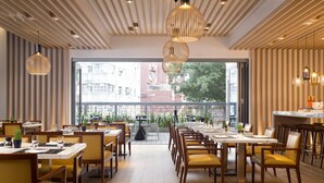 A modern dining area with wooden tables and chairs, large windows, and hanging pendant lights. - Hotel Indigo Hong Kong Island by IHG (Hong Kong)