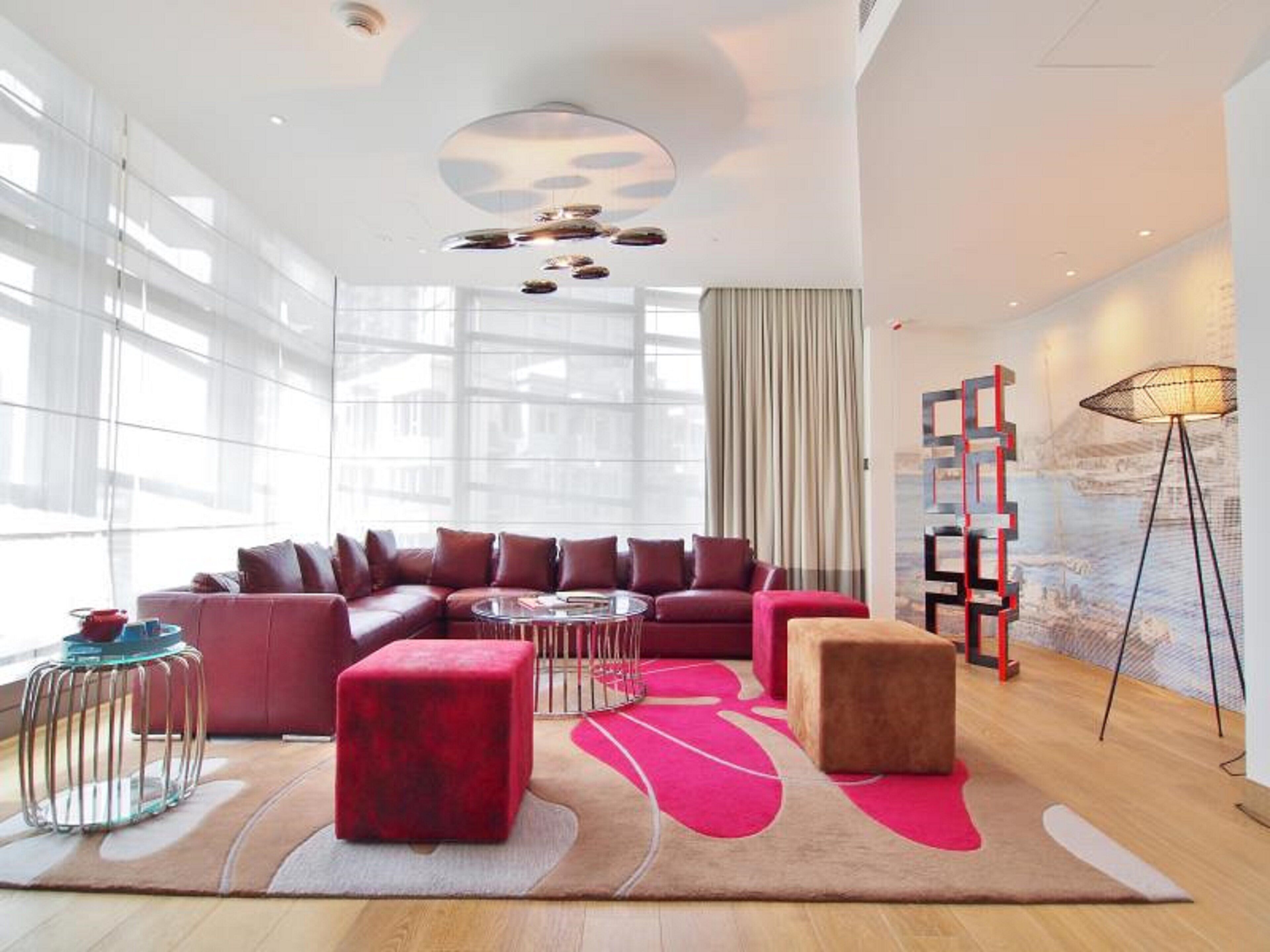 Uma sala de estar moderna com um sofá seccional, pufes, uma mesa de centro e um abajur.
