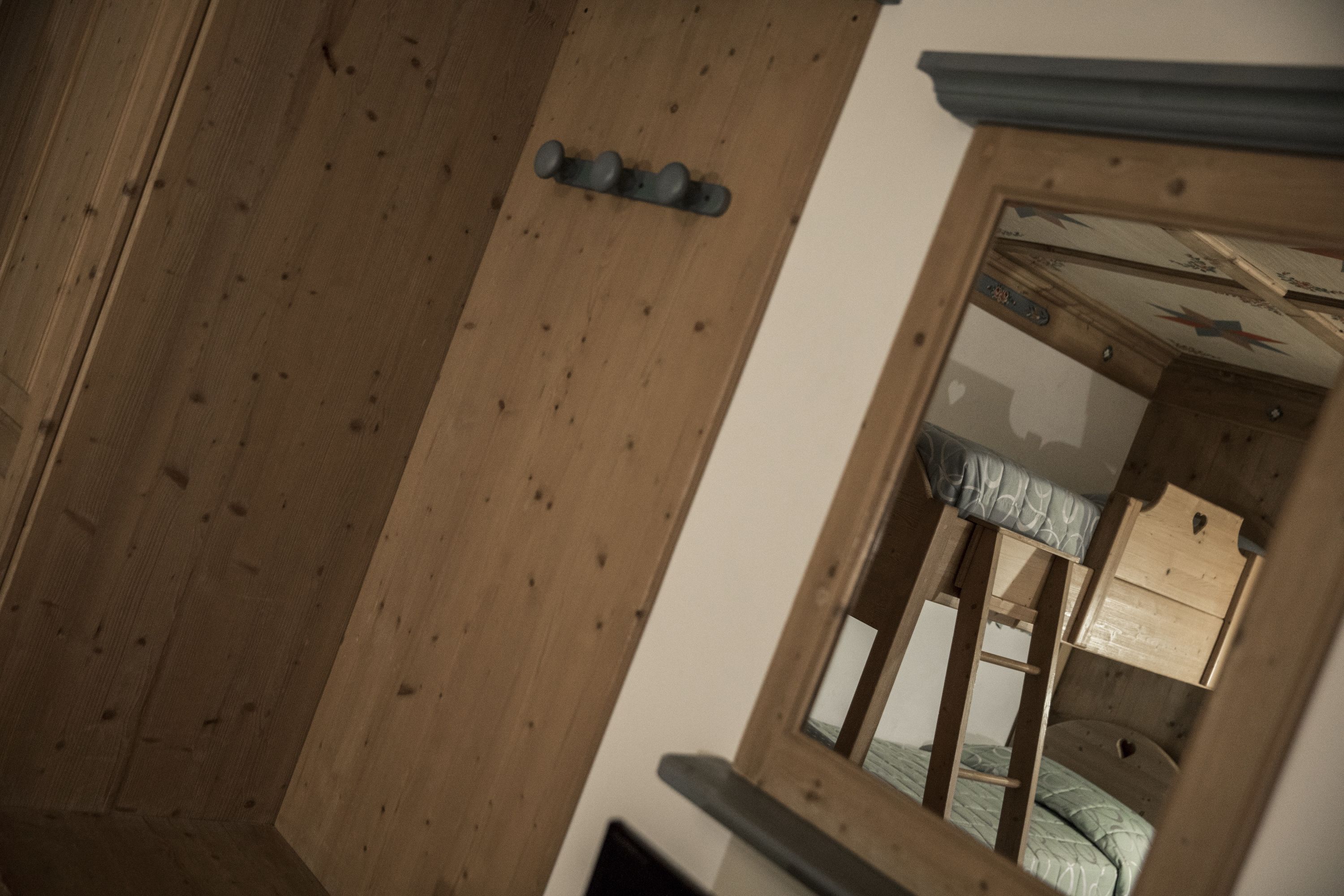 A wooden room with a bunk bed, a small window, and a mirror.