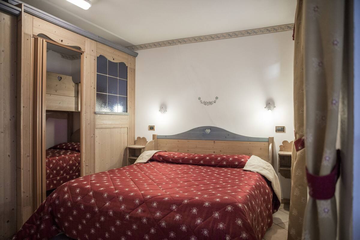 A bedroom with a wooden bed, a wardrobe, and a mirror.