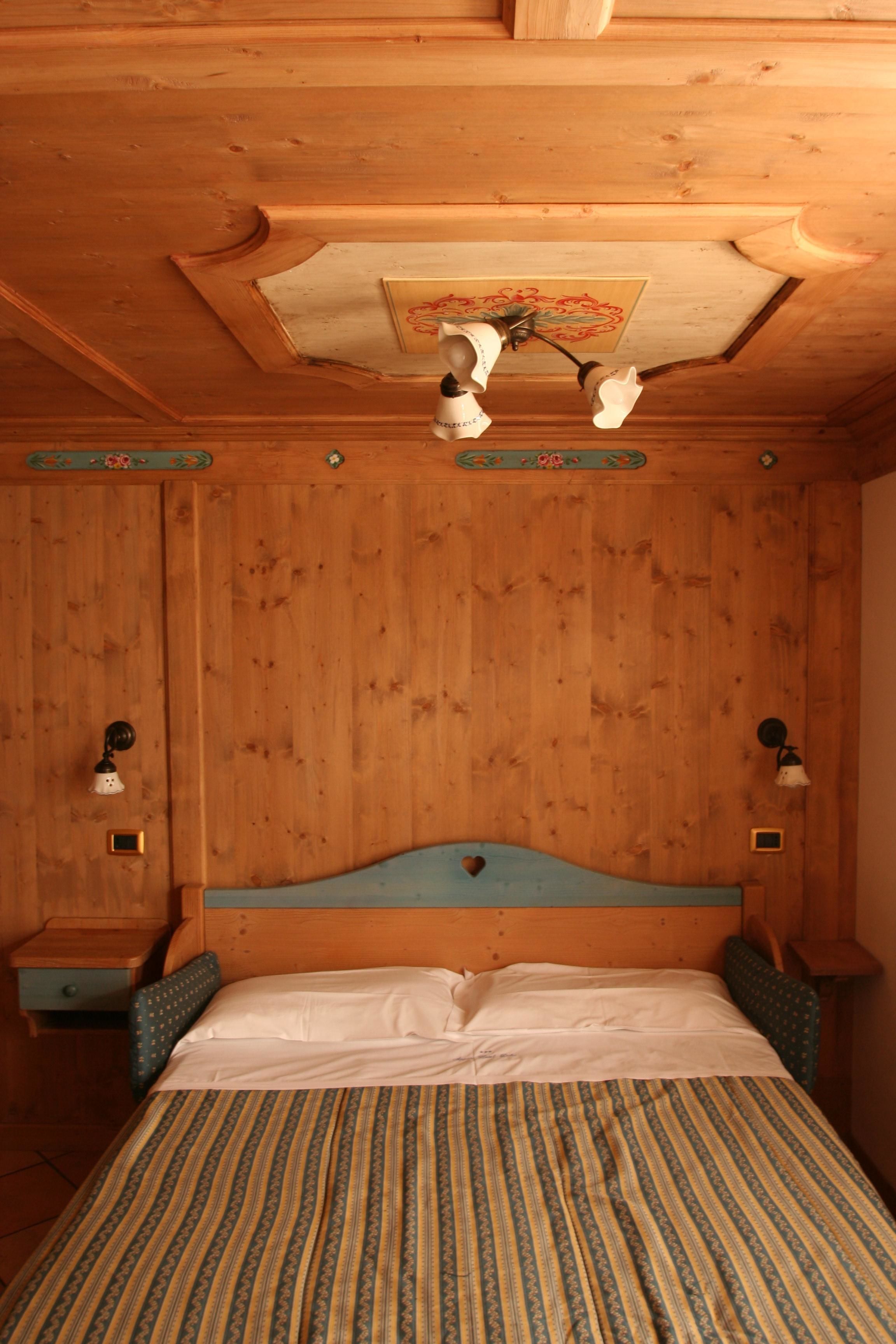 Una habitación con paneles de madera, una cama, dos mesitas de noche y un ventilador de techo.